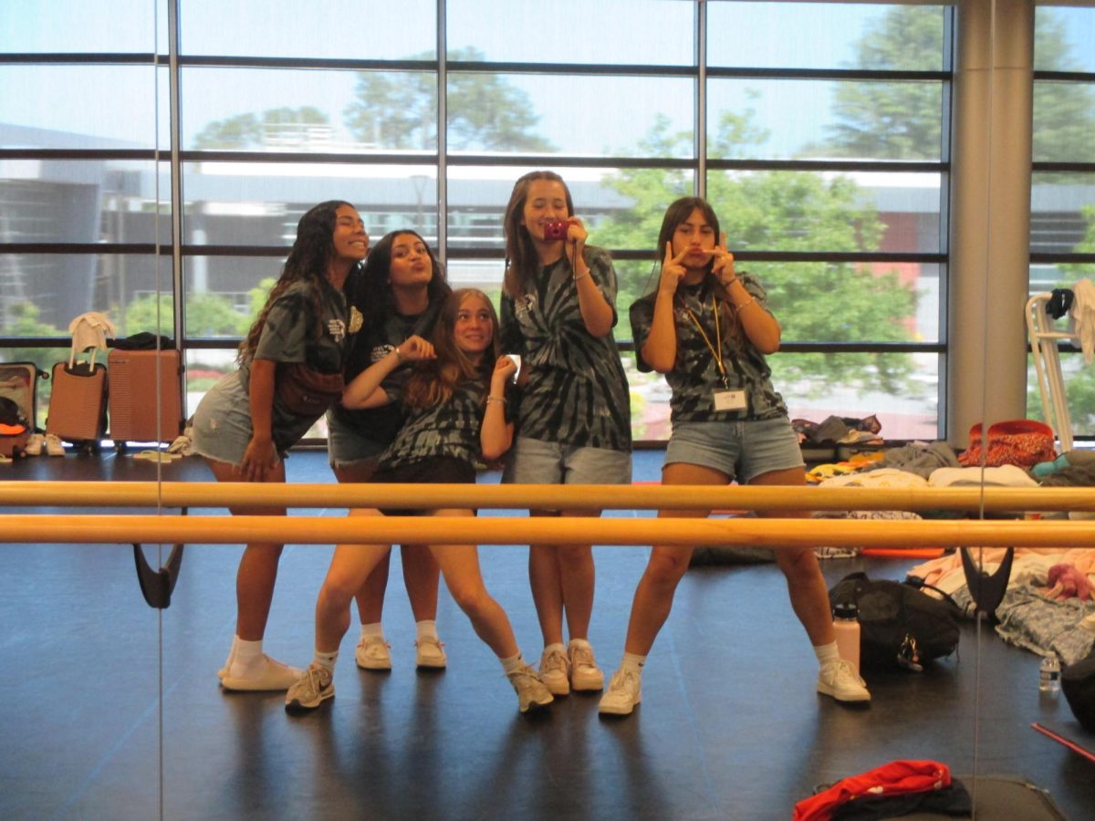 Five Holy Cross Immersion '24 participants posing in the Saint Francis dance room for a morning photo.