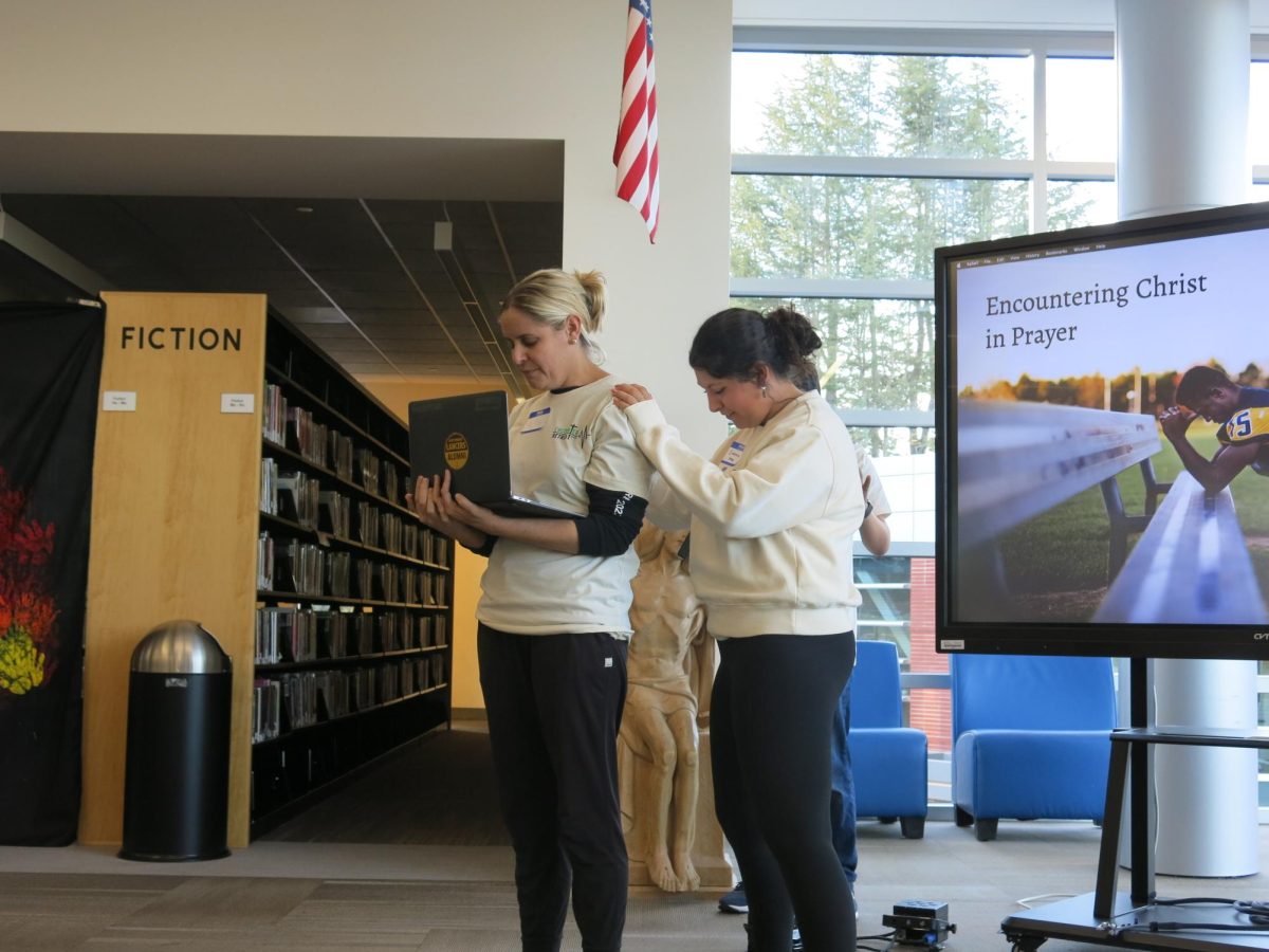 Emma Kluge('25) prays over Ms. Andrea Joslyn before her talk on encountering Christ through prayer.