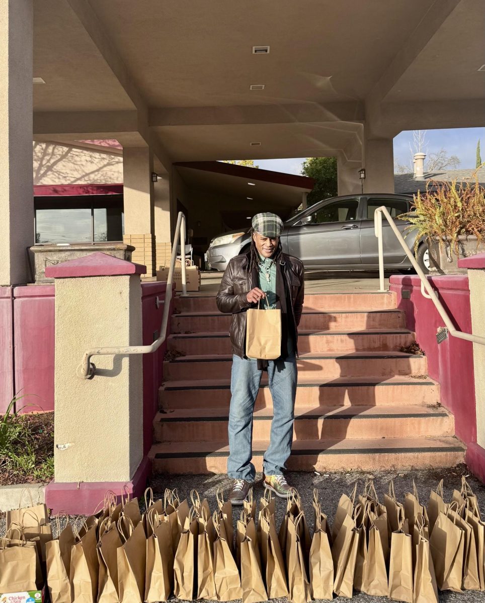 A volunteer stand in front of bags made during the Service Club’s Food Drive. 