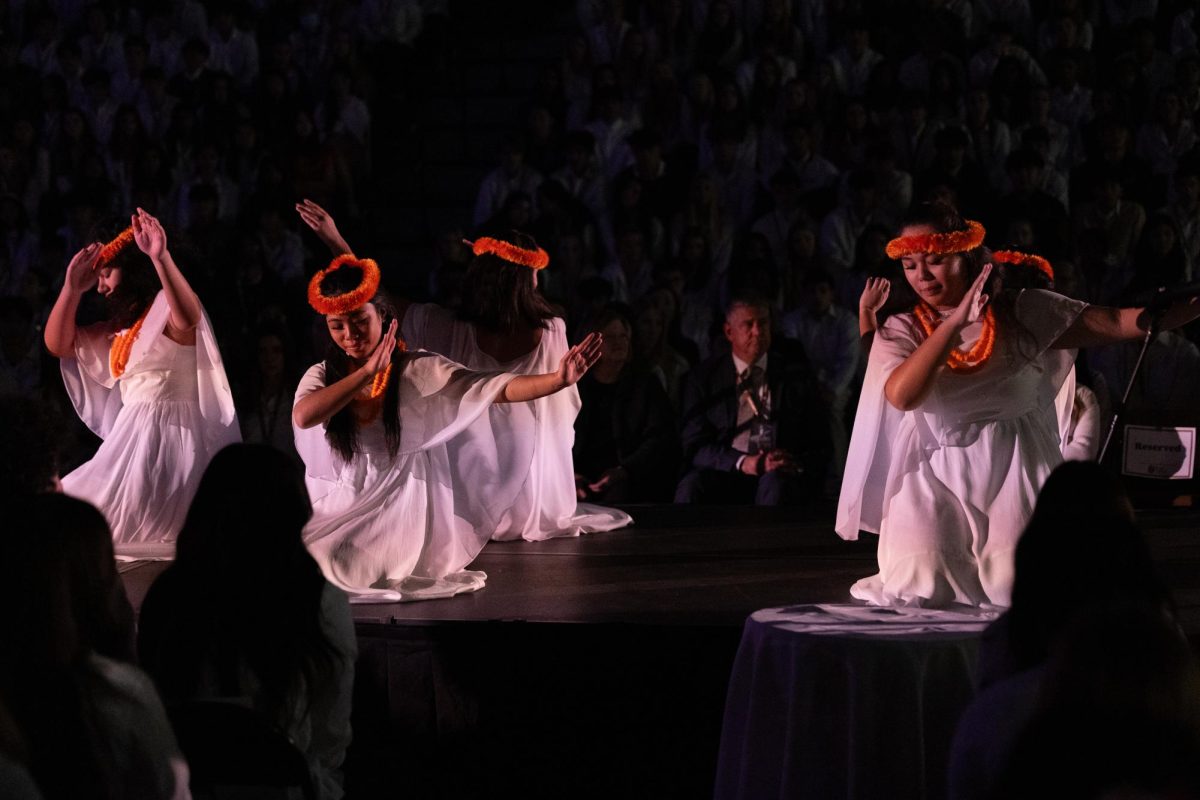 Tagata Pasifika performing a traditional Polynesian hula dressed in white outfits and orange leis.