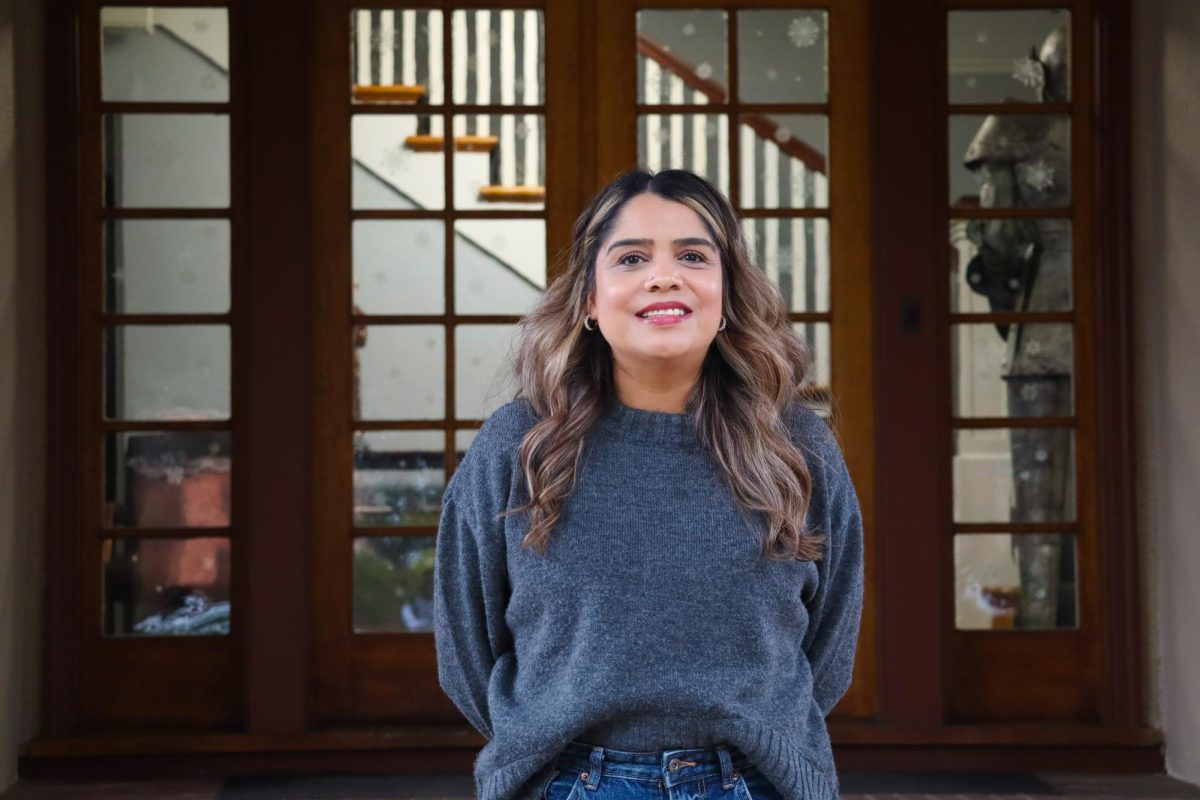 Maestra Karla Andrade smiles in front of the Andre House.